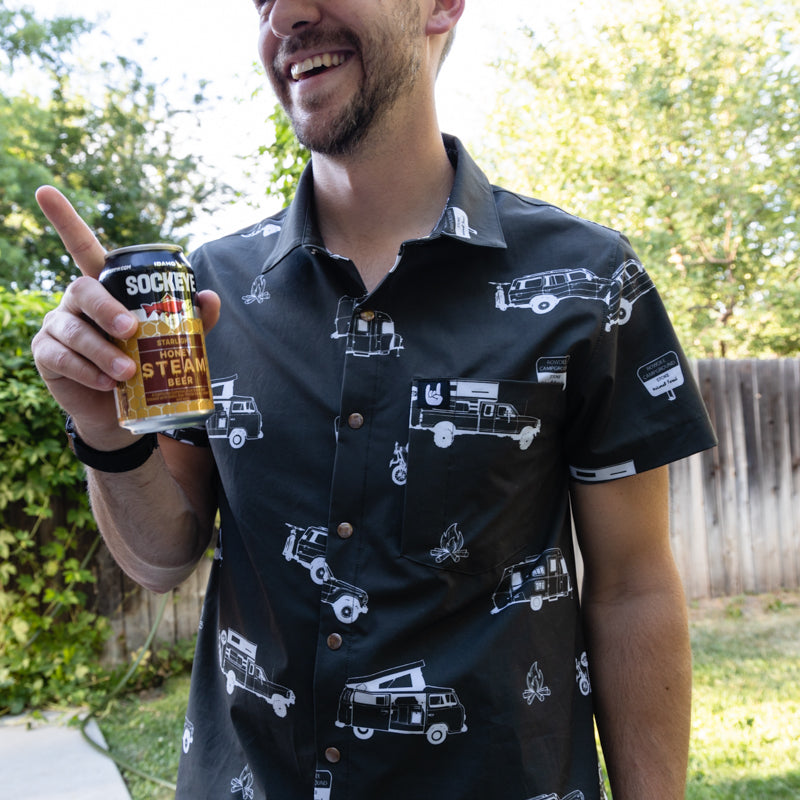 white man wearing rowdee weekender shirt in black holding a beer and smiling.