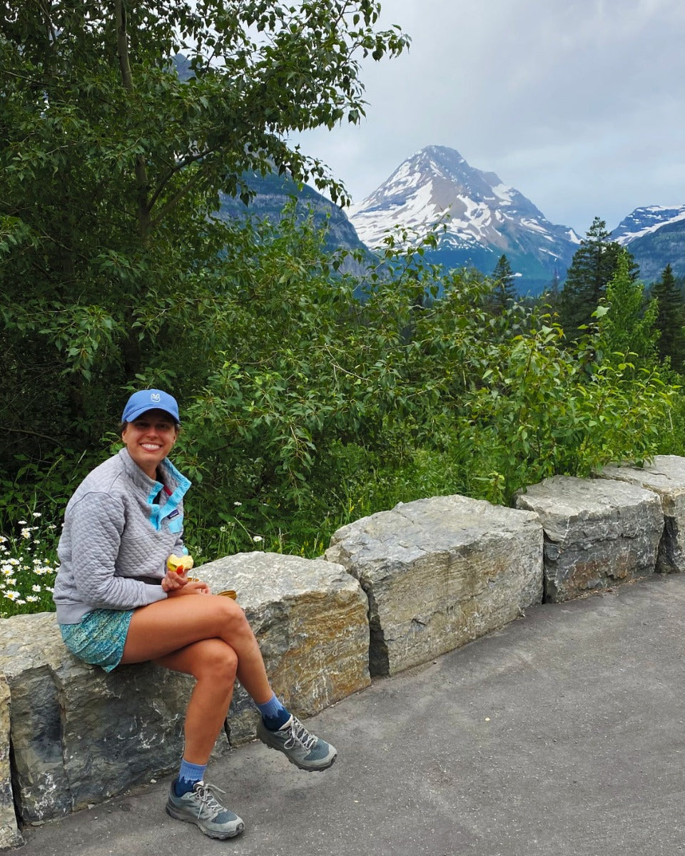 smiling woman wearing slate blue rowdee dad cap in glacier national park.